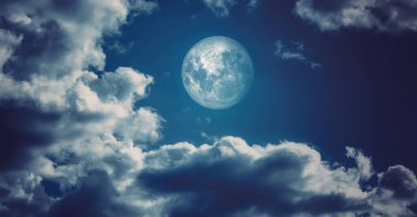 Büyük dolunay, gece karanlığında kabarık bulutlar arasında parlıyor. Gece görünümü.