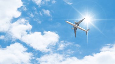 Yolcu uçağı ve mavi gökyüzünde parlayan güneş. Yaz mevsimi hava taşımacılığı.