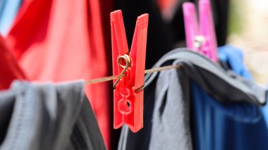 Sıcak bir yaz gününde balkonda çamaşır ipine asılı elbiseler ve kırmızı mandallar. Seçici odak.