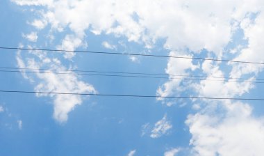 Mavi gökyüzü arka planında yüksek voltajlı güç hattı kabloları.