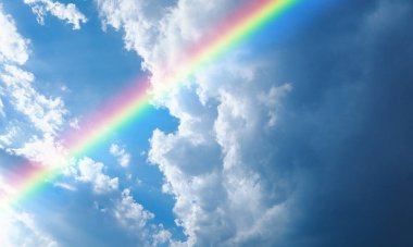 Yağmurdan sonra mavi gökyüzünde büyük gri bulutlar ve gökkuşağı.