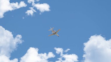 Gökyüzündeki beyaz bulutlar arasında yüksek irtifada uçan özel jet uçağı