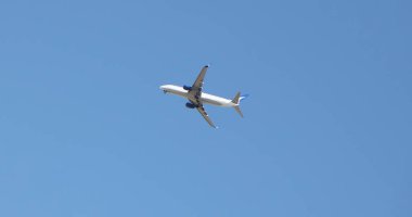 Bulutsuz mavi gökyüzünde havalandıktan hemen sonra yükselmeye başlayan yolcu uçağı..