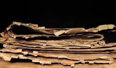 Eski, yırtık, katlanmış gazeteler siyah arka planda masanın üstünde..