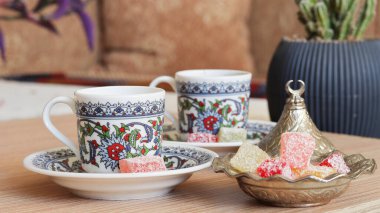 Gümüş bir kasede renkli Türk lezzetleri ve ahşap bir masada dekoratif bir fincanda Türk kahvesi. Türk kahvesi UNESCO tarafından elle tutulamaz bir Kültür Mirası olarak tanınıyor.