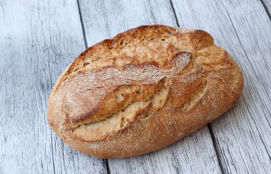 Beyaz ahşap arka planda büyük bir somun taze ekmek.