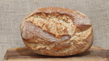 Tahta kesme tahtasının üzerinde yuvarlak bir somun ekmek. Taze pişmiş ekmeğin fotoğrafı..