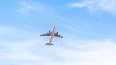 İnce bulutlara ve açık mavi gökyüzüne doğru uçan yolcu uçağı. Düşük açılı uçak manzarası..