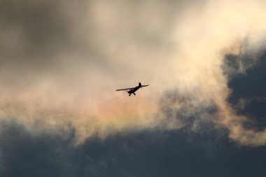 Gökyüzünde kara bulutlara karşı uçan küçük bir uçak.