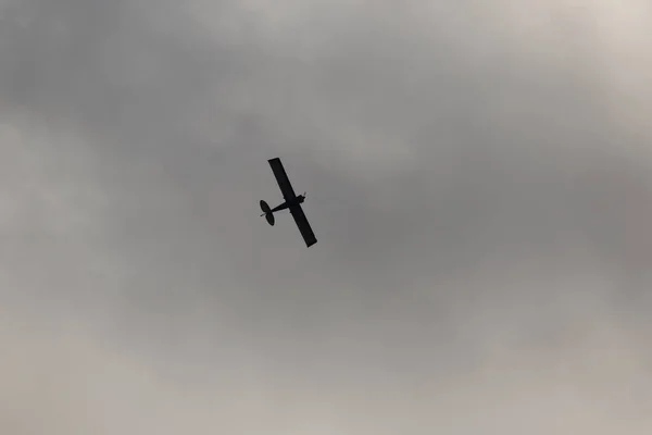 在乌云的映衬下在天空中飞行的小飞机 — 图库照片