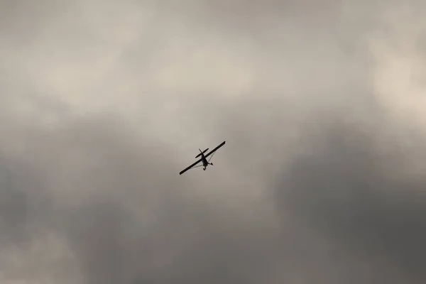 在乌云的映衬下在天空中飞行的小飞机 — 图库照片