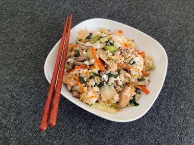 Bibimbap tabağı beyaz bir tabakta servis edilen et, pirinç, sebze ve yumurta.