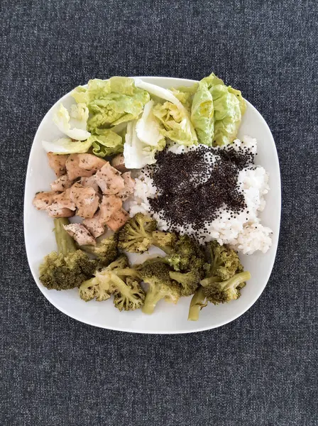 Beyaz tabakta servis edilen pilav ve brokoli ile ev yapımı ızgara tavuk.