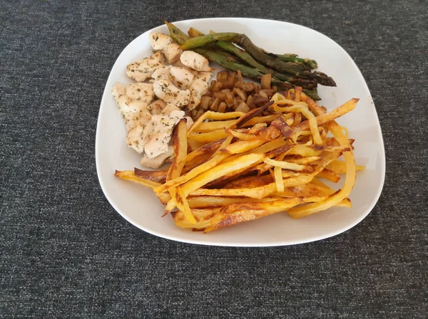 Homemade grilled chicken with french fries, eggplant and grilled asparagus, served on a white plate