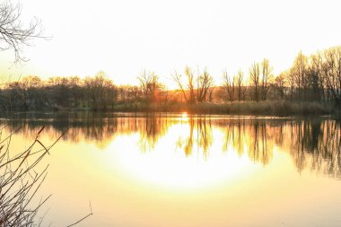 Sonbahar ağaçları göl boyunca altın ve kırmızı renkler sergilerler, sakin yansıtıcı suda güzel yansıtılır..
