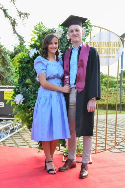 TIMISOARA, ROMANIA - 12 Temmuz 2022: Mezunlar, özel tören sırasında gülümseme ve anılarını paylaşan aile ve misafirlerle birlikte gururla parkta toplandılar.