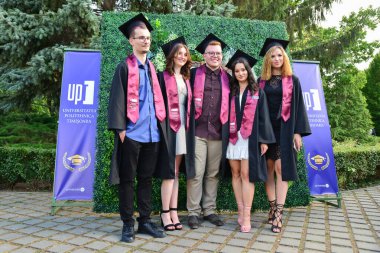 TIMISOARA, ROMANIA - 12 Temmuz 2022: Mutlu öğrenciler üniversite mezuniyetlerini arkadaşlarıyla ve aileleriyle birlikte kutlayan hatırlanmaya değer fotoğraflar için poz veriyorlar.