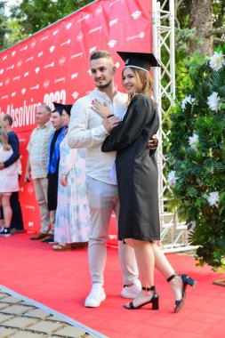 TIMISOARA, ROMANIA - 12 Temmuz 2022: Mezunlar, özel tören sırasında gülümseme ve anılarını paylaşan aile ve misafirlerle birlikte gururla parkta toplandılar.