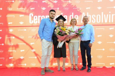 TIMISOARA, ROMANIA - 12 Temmuz 2022: Mezunlar, özel tören sırasında gülümseme ve anılarını paylaşan aile ve misafirlerle birlikte gururla parkta toplandılar.