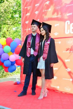 TIMISOARA, ROMANIA - 12 Temmuz 2022: Mutlu öğrenciler üniversite mezuniyetlerini arkadaşlarıyla ve aileleriyle birlikte kutlayan hatırlanmaya değer fotoğraflar için poz veriyorlar.