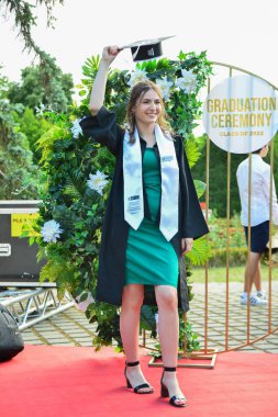 TIMISOARA, ROMANIA - 12 Temmuz 2022: Akademik kıyafetiyle gülümseyen genç bir kadın başarı ve umut dolu yeni başlangıçların anılarını yakalıyor