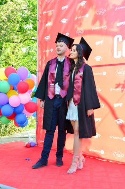 TIMISOARA, ROMANIA - 12 Temmuz 2022: Mutlu öğrenciler üniversite mezuniyetlerini arkadaşlarıyla ve aileleriyle birlikte kutlayan hatırlanmaya değer fotoğraflar için poz veriyorlar.