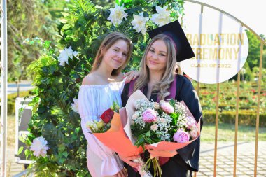 TIMISOARA, ROMANIA - 12 Temmuz 2022: Mezunlar, özel tören sırasında gülümseme ve anılarını paylaşan aile ve misafirlerle birlikte gururla parkta toplandılar.