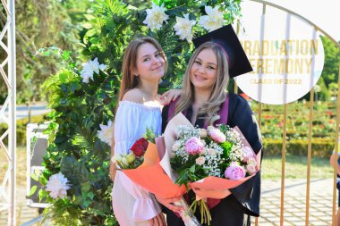 TIMISOARA, ROMANIA - 12 Temmuz 2022: Mezunlar, özel tören sırasında gülümseme ve anılarını paylaşan aile ve misafirlerle birlikte gururla parkta toplandılar.