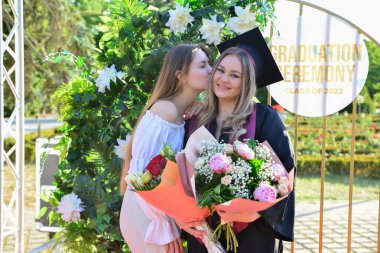 TIMISOARA, ROMANIA - 12 Temmuz 2022: Mezunlar, özel tören sırasında gülümseme ve anılarını paylaşan aile ve misafirlerle birlikte gururla parkta toplandılar.