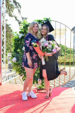 TIMISOARA, ROMANIA - 12 Temmuz 2022: Mezunlar, özel tören sırasında gülümseme ve anılarını paylaşan aile ve misafirlerle birlikte gururla parkta toplandılar.