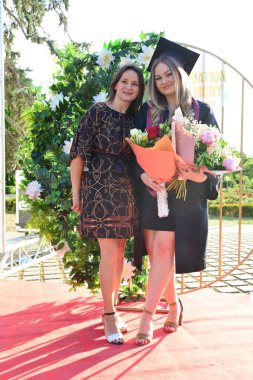 TIMISOARA, ROMANIA - 12 Temmuz 2022: Mezunlar, özel tören sırasında gülümseme ve anılarını paylaşan aile ve misafirlerle birlikte gururla parkta toplandılar.