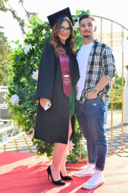 TIMISOARA, ROMANIA - 12 Temmuz 2022: Mezunlar, özel tören sırasında gülümseme ve anılarını paylaşan aile ve misafirlerle birlikte gururla parkta toplandılar.