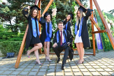 TIMISOARA, ROMANIA - 12 Temmuz 2022: Mutlu öğrenciler üniversite mezuniyetlerini arkadaşlarıyla ve aileleriyle birlikte kutlayan hatırlanmaya değer fotoğraflar için poz veriyorlar.