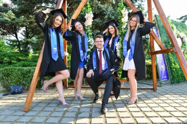 TIMISOARA, ROMANIA - 12 Temmuz 2022: Mutlu öğrenciler üniversite mezuniyetlerini arkadaşlarıyla ve aileleriyle birlikte kutlayan hatırlanmaya değer fotoğraflar için poz veriyorlar.