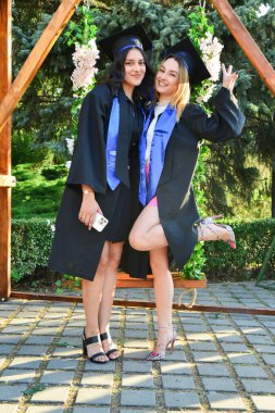 TIMISOARA, ROMANIA - 12 Temmuz 2022: İki genç kadın başarılarını kutlamak için mezuniyet töreninde mutlu poz verdiler