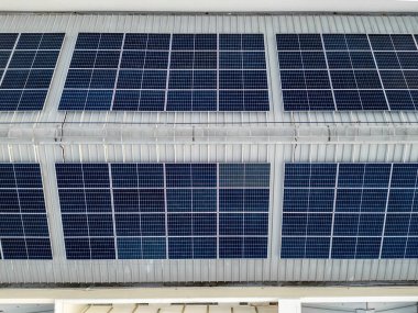 Büyük endüstriyel fabrika binasının çatısındaki ya da bir depodaki mavi güneş enerjili voltaik panellerin hava görüntüsü. Yenilenebilir ekolojik yeşil enerji üretim kavramı.