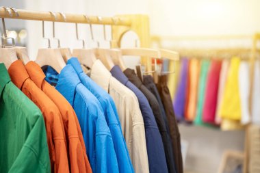 Renkli pamuklu takım elbiseler, korkuluktaki ahşap kumaş askısıyla asılır. Moda yaşam tarzı nesnesi, yakın plan ve seçici odaklanma