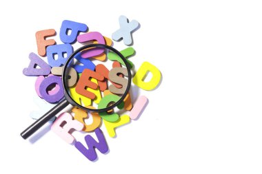 English alphabet made of square wooden tiles with the English alphabet scattered on white background. The concept of thinking development, grammar. Magnifier placed on English letters