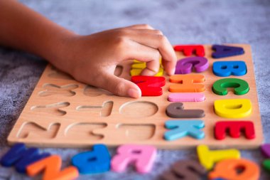English alphabet made of square wooden tiles with the English alphabet scattered on hand. The concept of thinking development, grammar