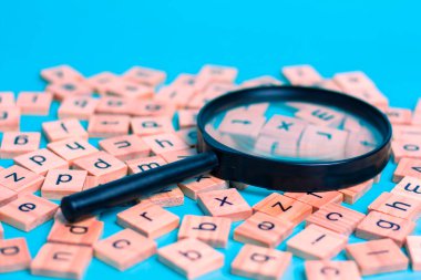 English alphabet made of square wooden tiles with the English alphabet scattered on blue background. The concept of thinking development, grammar