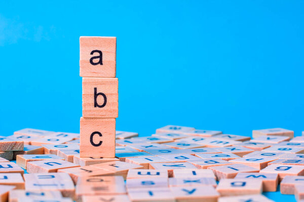English alphabet made of square wooden tiles with the English alphabet scattered on blue background. The concept of thinking development, grammar