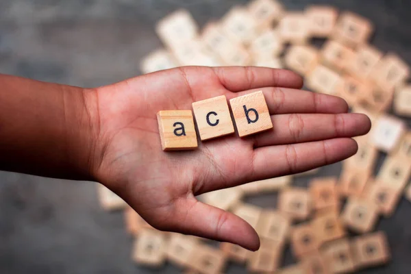 English alphabet made of square wooden tiles with the English alphabet scattered on hand. The concept of thinking development, grammar