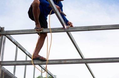 Home roof frame welder. concept working at unsafe height. not wear protective equipment to work.