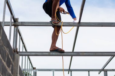 Home roof frame welder. concept working at unsafe height. not wear protective equipment to work.