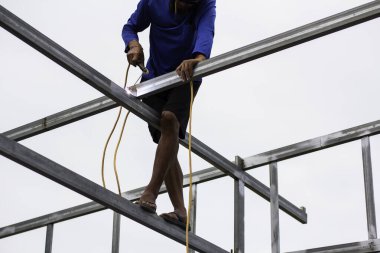 Home roof frame welder. concept working at unsafe height. not wear protective equipment to work.