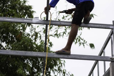 Home roof frame welder. concept working at unsafe height. not wear protective equipment to work.