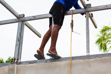 Home roof frame welder. concept working at unsafe height. not wear protective equipment to work.