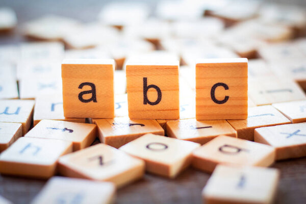 English alphabet made of square wooden tiles with the English alphabet scattered on table. The concept of thinking development, grammar