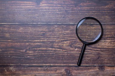 Magnifier placed on a wooden table, there is free space.
