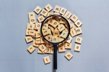 Kare ahşap karolardan yapılmış İngiliz alfabesi mavi arkaplana saçılmış. Düşünce geliştirme konsepti, dil bilgisi.